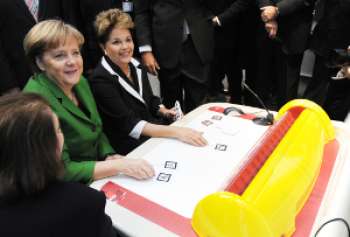 La canciller alemana Angela Merkel y la presidente de Brasil Dilma Rousseff usando la innovadora solución eBlocks de la empresa brasileña Positivo Informática durante su recorrido por la feria. Foto cortesía CeBIT