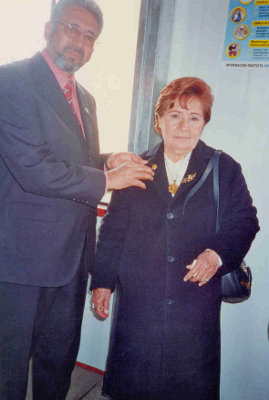 El ex-alumno representante de la Asociación  Carvajalina Héctor Torres condecora a la Directora actual de "Melitón Carvajal" con "El Broche de Oro"