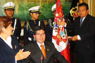 Condecoran el estandarte nacional con la Medalla de Honor del Congreso. Observan la Directora del MC, el Congresista Wilson Michael Urtecho y el Mg. José Urquizo Muggia congresista y ex-alumno MC-83. Al fondo alumnos de la Escolta del colegio MC observan atentamente