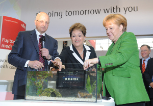 La canciller alemana Angela Merkel y la presidente de Brasil Dilma Rousseff comprobando que una computadora portátil de tipo tableta es a prueba de agua, así como lo aseguró su fabricante. Foto cortesía CeBIT